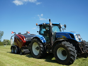 Stor blå Hew Holland traktor til maskinstationen kører og wrapper wrapballer